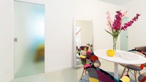 A modern room with a round table, colorful chairs, a vase of flowers, and a mirror on the wall. - Casa Bella Pantheon (Rome)