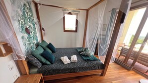 A bedroom with a four-poster bed, a wooden nightstand, and a large window with a view of the outdoors. - Panoramic Sea View. Take a walk to the medieval village. (Tourrettes-Sur-Loup)