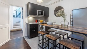 A modern kitchen with dark cabinetry, a microwave, a washing machine, and a dining area with stools.