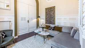 A modern living room with a grey sofa, a round coffee table, and a patterned rug.