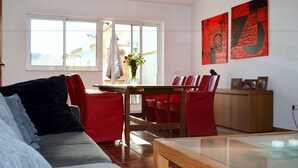 A modern living room with red furniture, a dining area with a wooden table, and a view of the outside through large windows. - B&B Casa AriGiLi (Fuengirola)