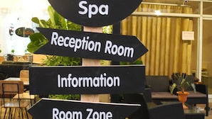 A signpost with directions to various areas of a hostel and spa, including reception, information, room zone, and café & massage. - Bann Tawan Hostel Chiang Rai (Chiang Rai)