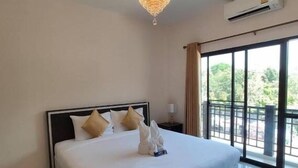 A hotel room with a large bed, a chandelier, an air conditioning unit, and a view of greenery through the window. - Bann Tawan Hostel Chiang Rai (Chiang Rai)