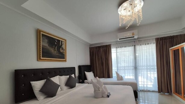 A hotel room with two beds, a chandelier, an air conditioning unit, and a painting on the wall. - Bann Tawan Hostel Chiang Rai (Chiang Rai)