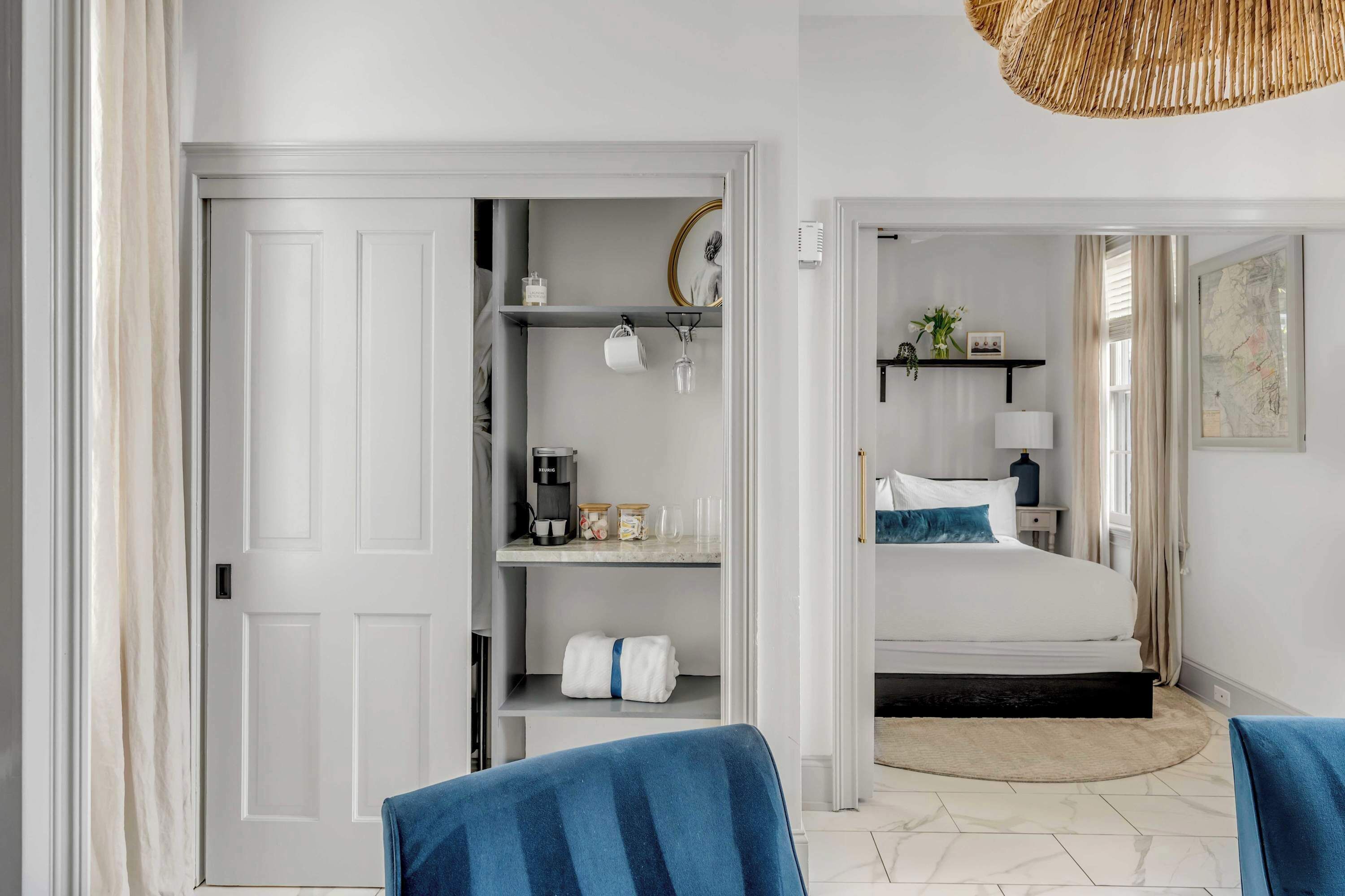 A hotel room with a bed, a wardrobe, a desk, and a chair.