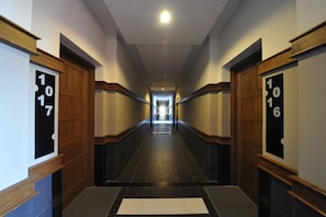 A long, narrow hallway with wooden doors on either side, each marked with a number.