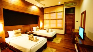 Quarto de hotel com duas camas, cabeceiras de madeira, uma televisão e uma janela com cortinas estampadas.
