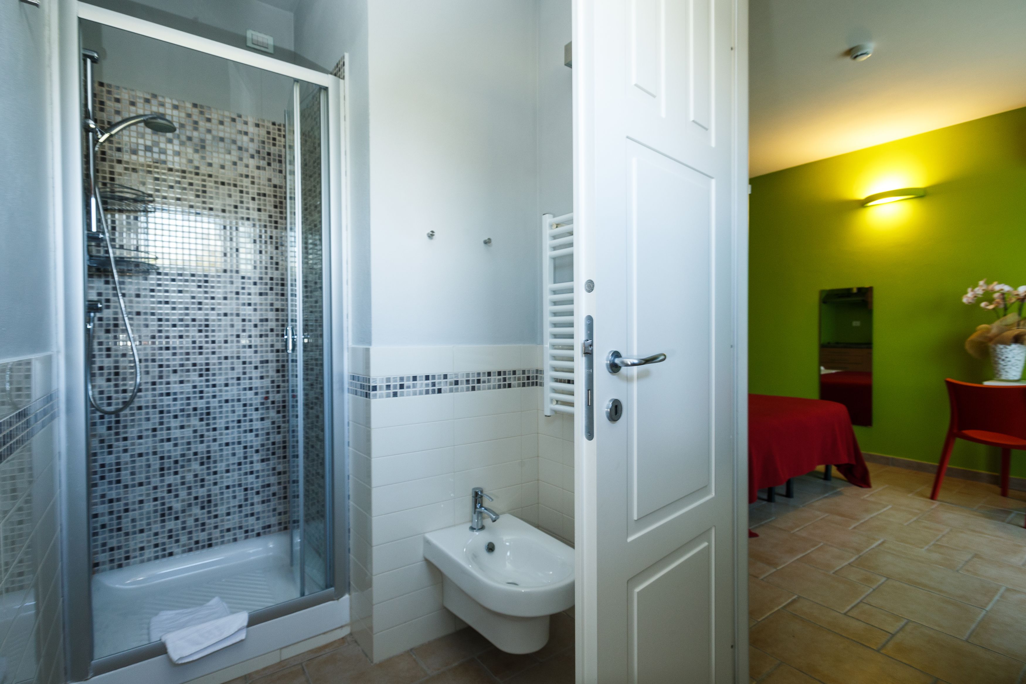 A bathroom with a glass shower enclosure, a bidet, and a white sink.