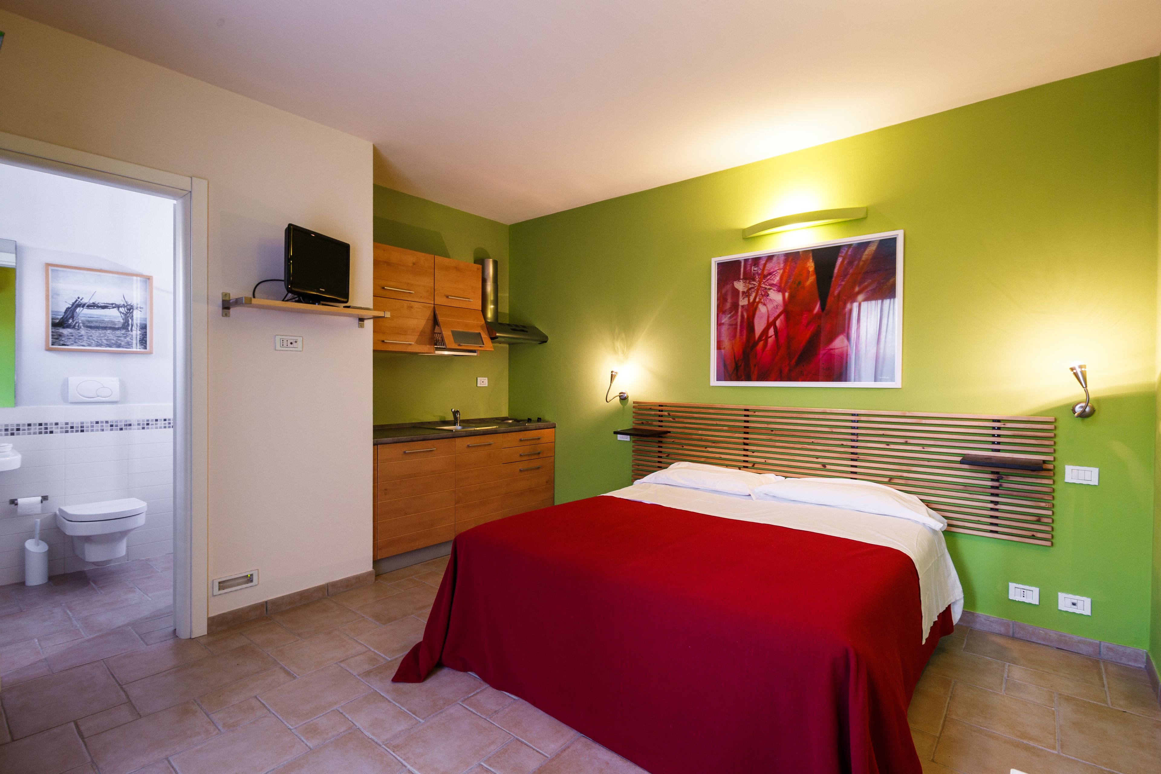 A bedroom with a bed, a bathroom, and a kitchenette.