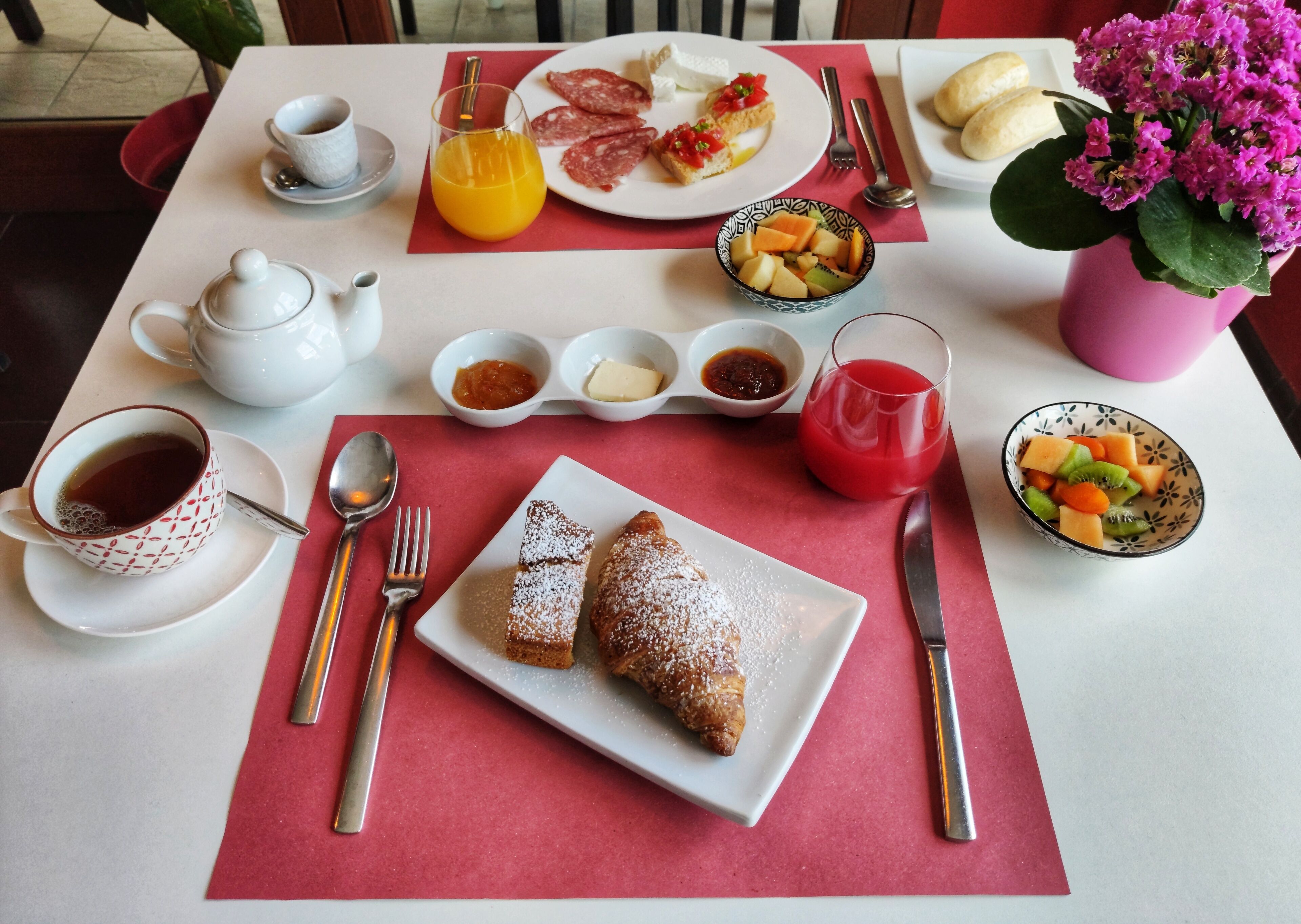 Een ontbijttafel met diverse soorten eten, zoals gebak, fruit en drankjes.