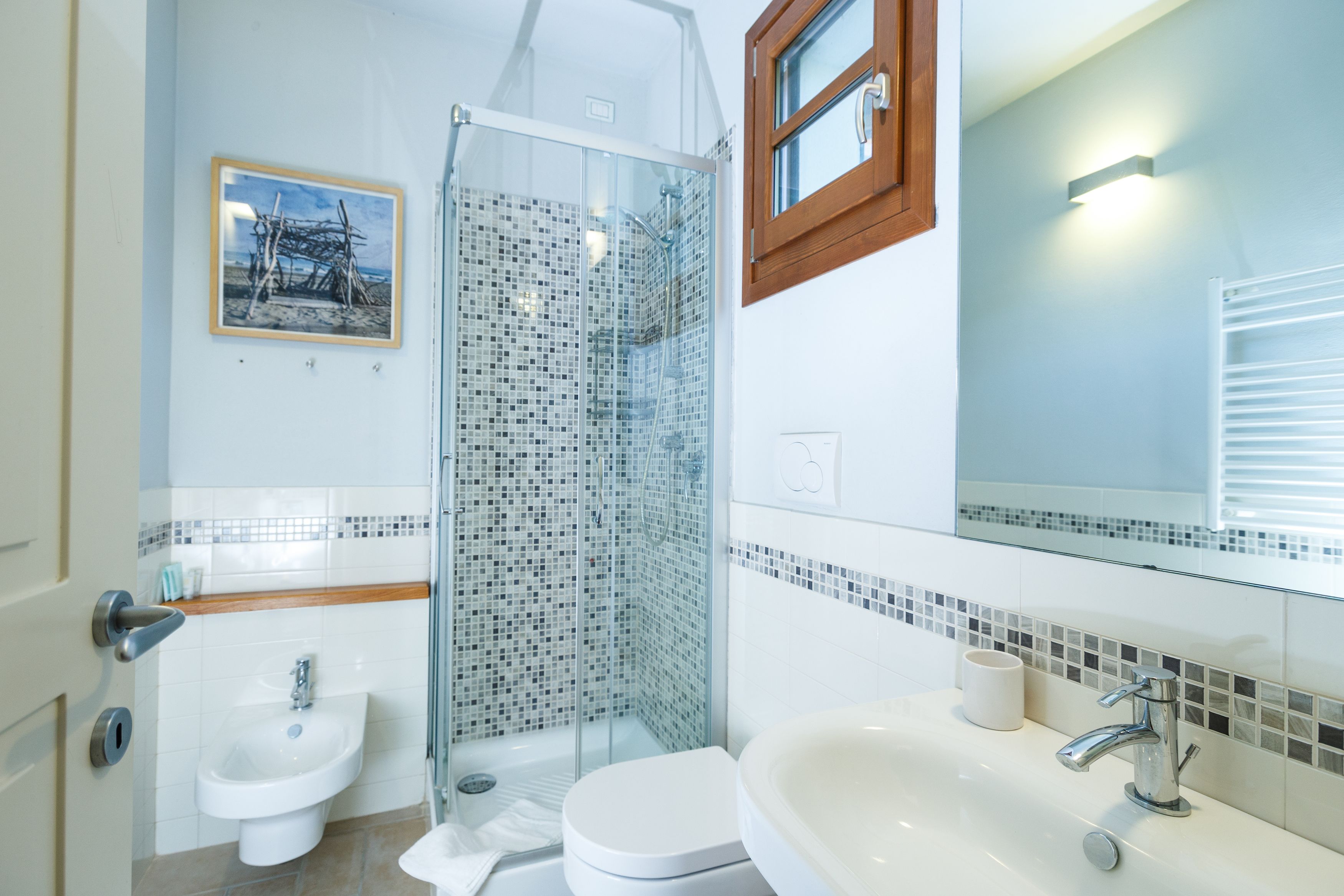 A modern bathroom with a glass shower, a sink, and a toilet.