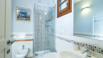 A modern bathroom with a glass shower, a sink, and a toilet.