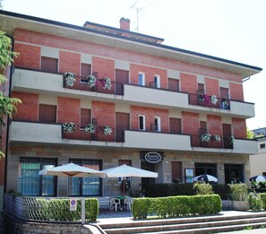 A multi-story building with a brick facade, outdoor seating area with umbrellas, and a sign for 'Albergo Maria'. - Albergo Da Mario (Pianoro)