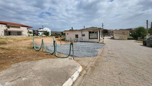 A residential area with houses, a small building with a sign, and a paved road. - Mahzen Küçükköy (Ayvalik)