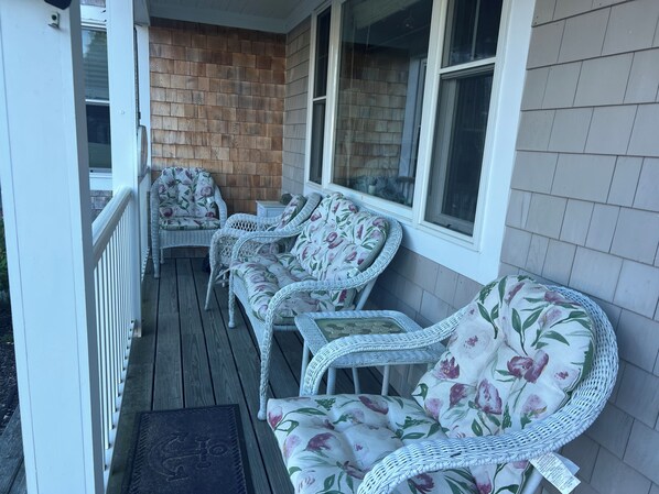 A covered porch with wicker furniture and a brick wall.
