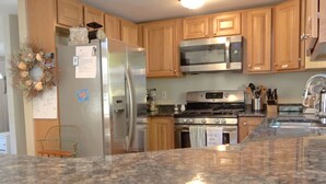 Una cocina con armarios de madera, un refrigerador de acero inoxidable, un microondas y una estufa.