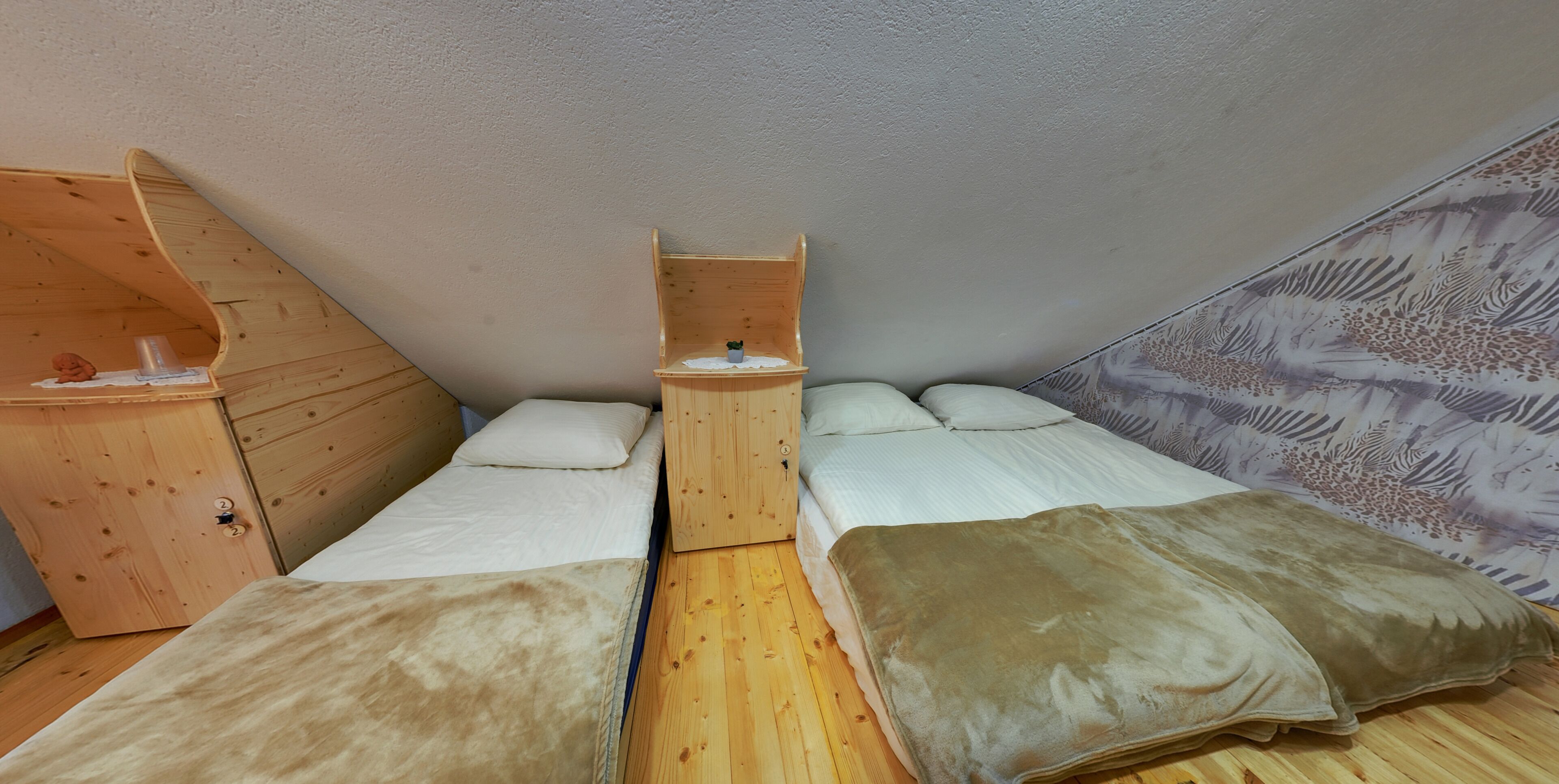 A compact room with two beds, a wooden wardrobe, and a small table.
