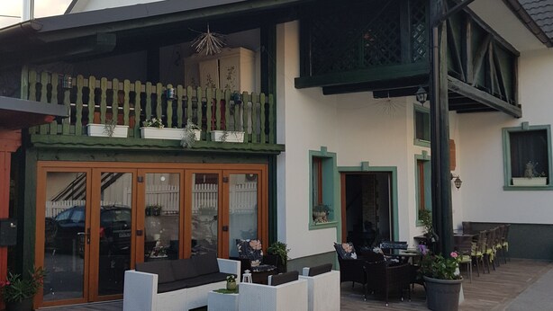 Un edificio de dos pisos con balcón, zona de estar al aire libre y patio cubierto.