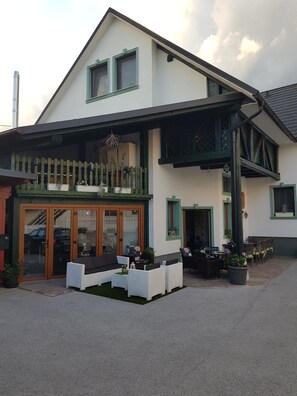 A two-story building with a balcony, outdoor seating area, and a covered patio. - Hostel Mama's House (Cerklje na Gorenjskem)