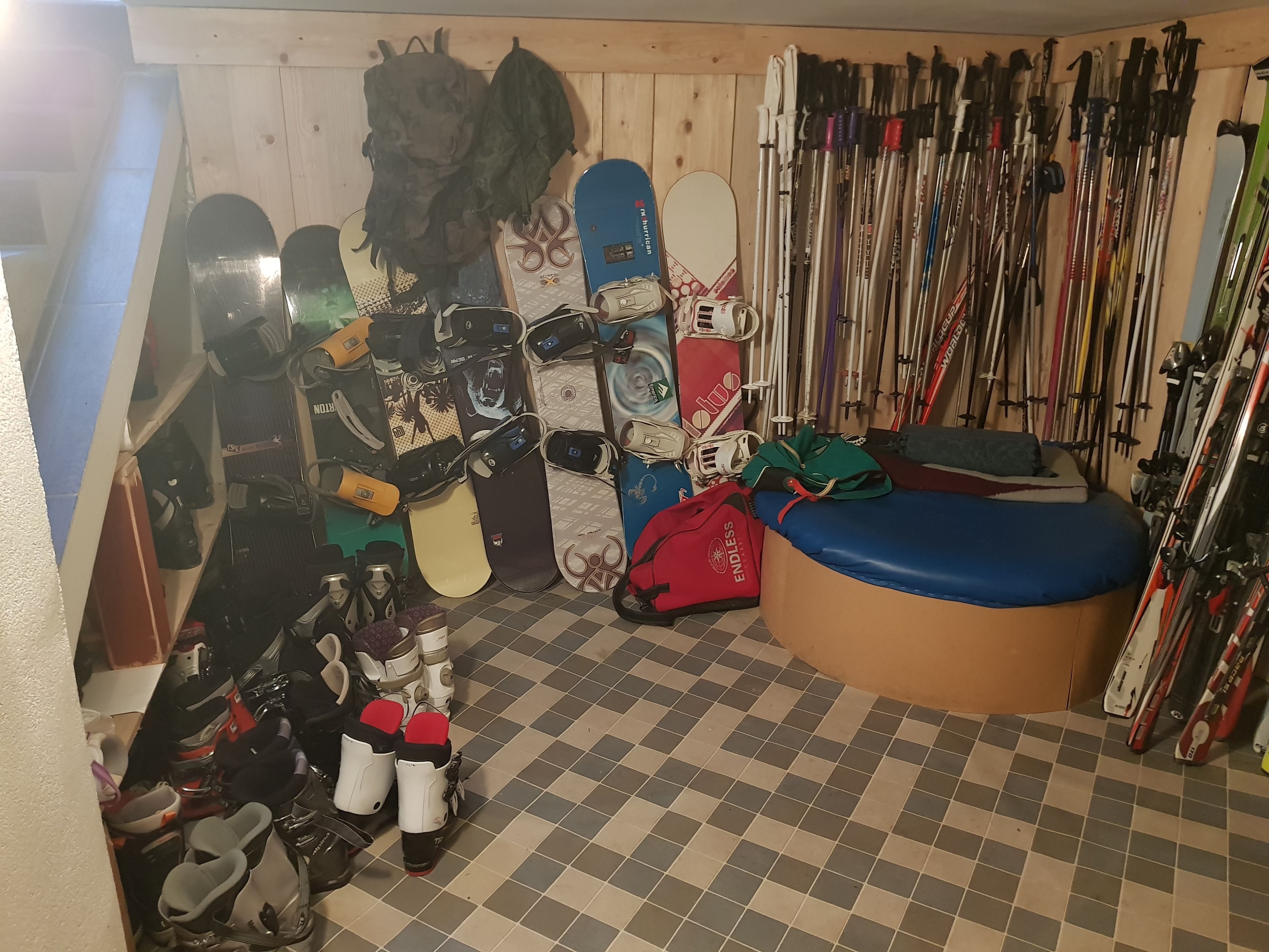 A ski storage room with multiple snowboards, skis, and ski poles.