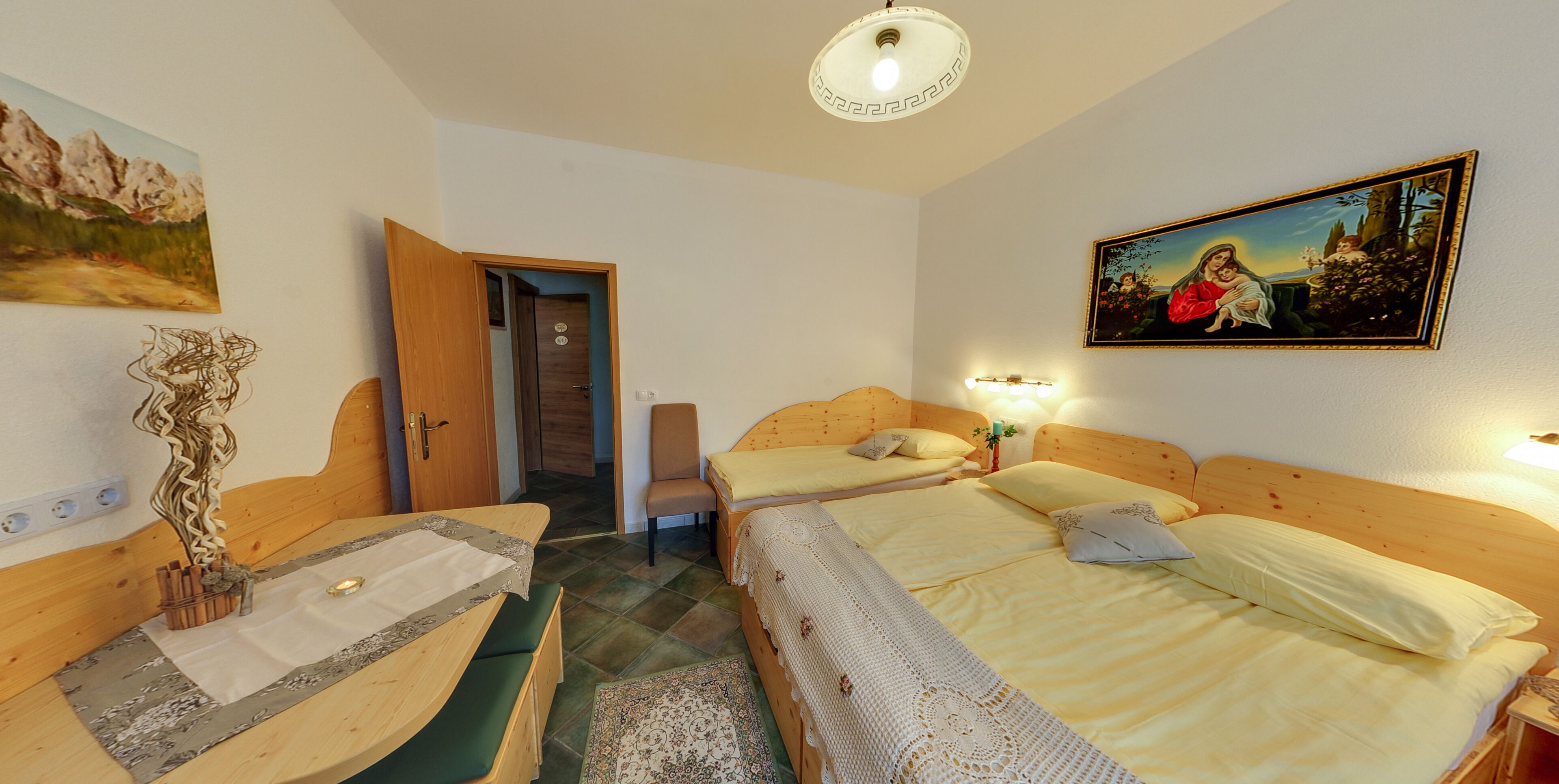 Ein Schlafzimmer mit zwei Betten, einem Holz-Kopfteil, einem Sessel, einem kleinen Tisch und einem Bild an der Wand.