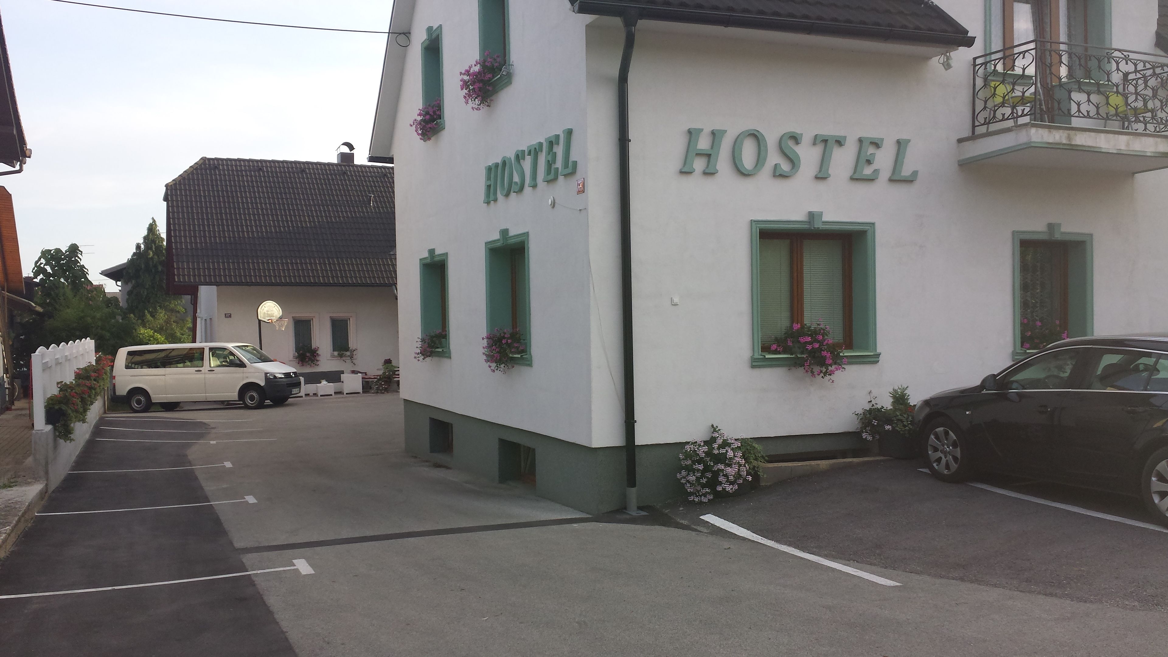 Un bâtiment blanc avec le mot «AUBERGE» écrit sur la façade, des encadrements de fenêtres verts et des jardinières.