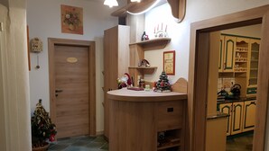 Un interior de madera con un mostrador redondo, un pequeño árbol de Navidad y una puerta con placa.