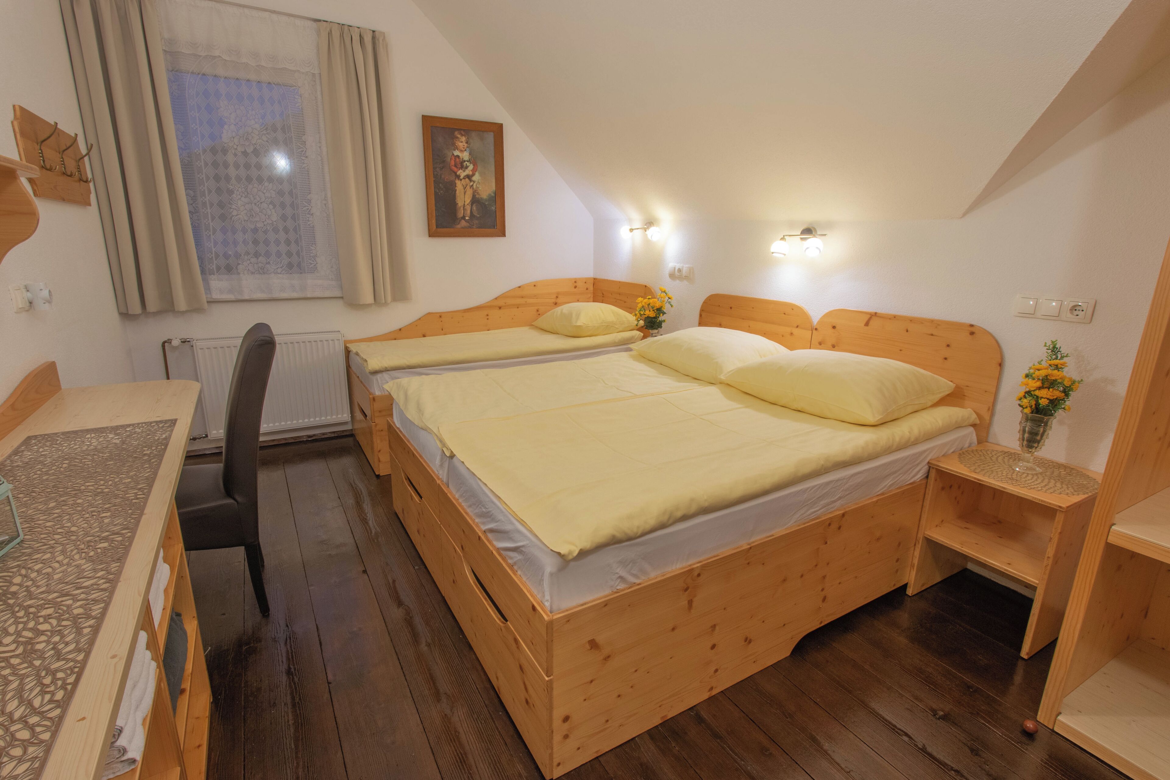 A bedroom with two wooden beds, a desk, and a chair.