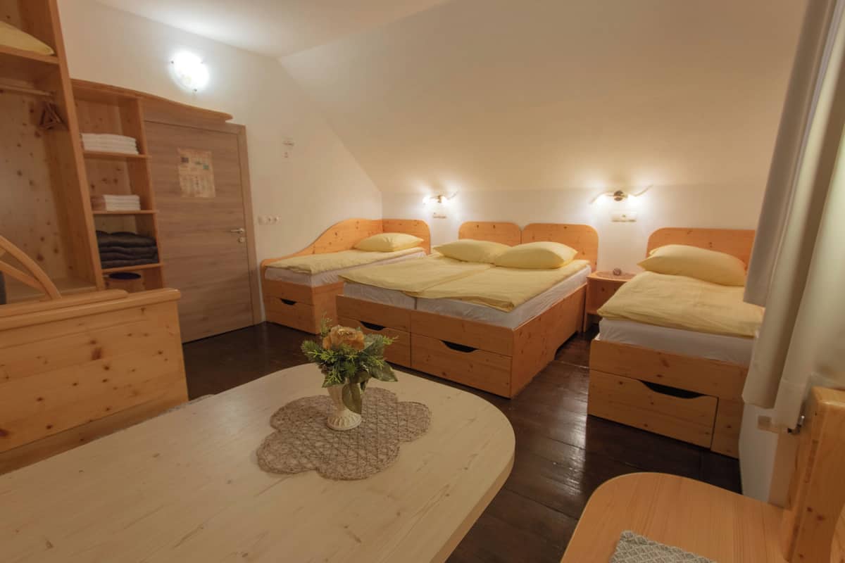 A cozy room with two wooden beds, a wooden wardrobe, a small table with a vase of flowers, and a wooden chair.