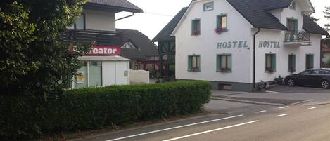 Een hostel met een witte gevel, groene raamkozijnen en bloembakken.