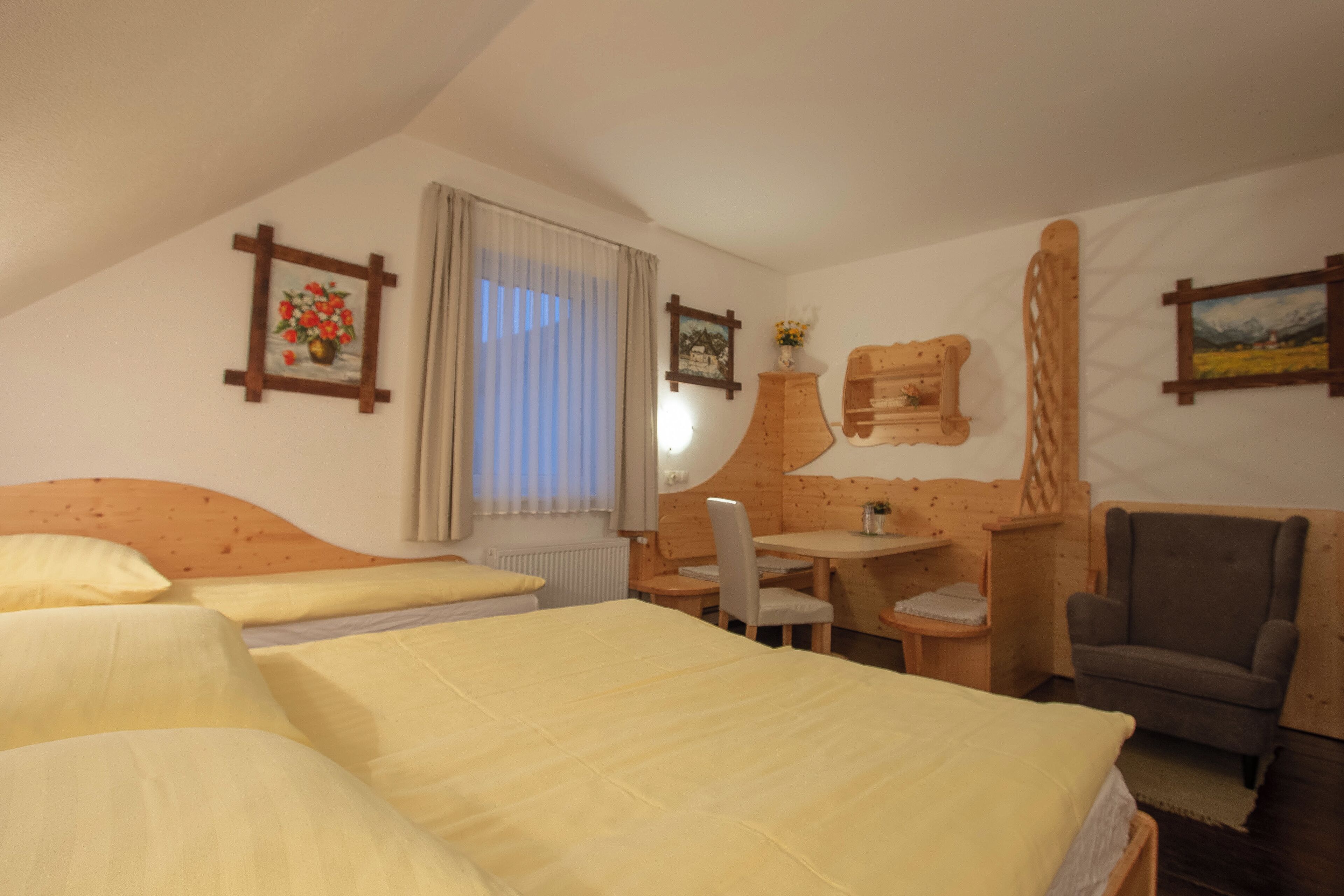 A room with two beds, a wooden desk, a chair, and a small table.