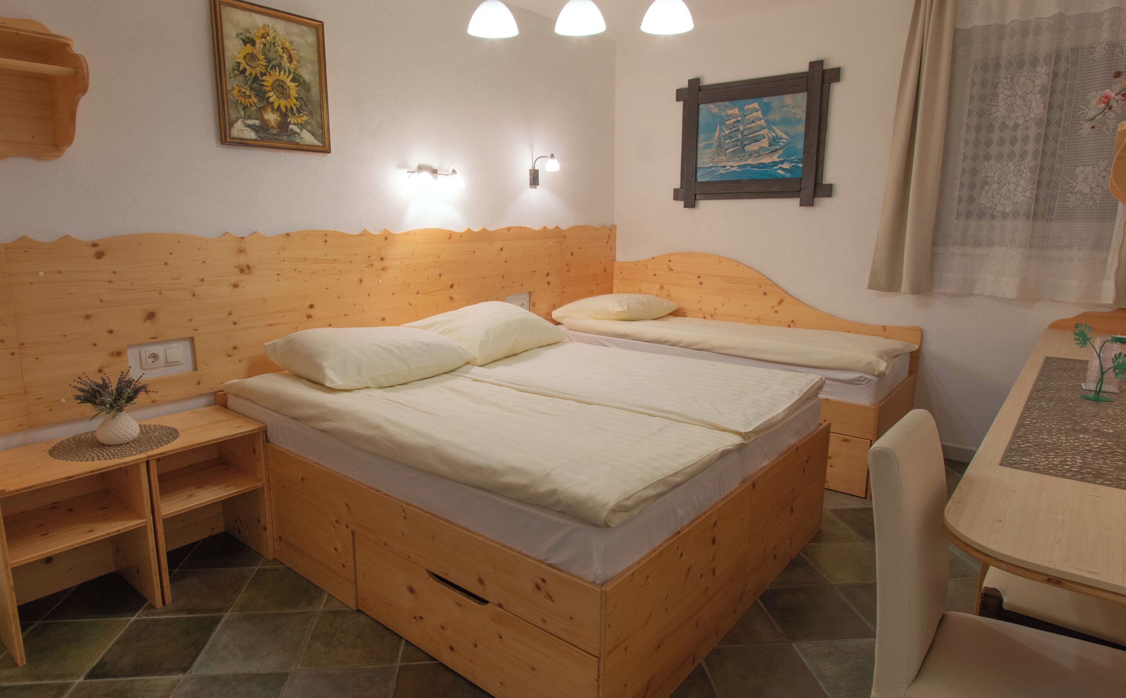 A wooden room with two beds, a small table, and a chair.