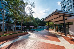 A courtyard with a swimming pool, outdoor seating, and modern buildings. - Spacious Three Bedroom Condo Cyberjaya (Cyberjaya)