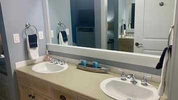 A bathroom with two sinks, a large mirror, and wooden cabinetry.