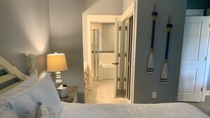 Habitación de hotel con cama, mesita de noche con lámpara, puerta y pared con dos tablas de remo.
