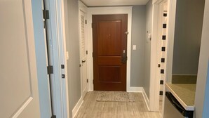 Un pasillo con una puerta de madera, una puerta blanca y un refrigerador.