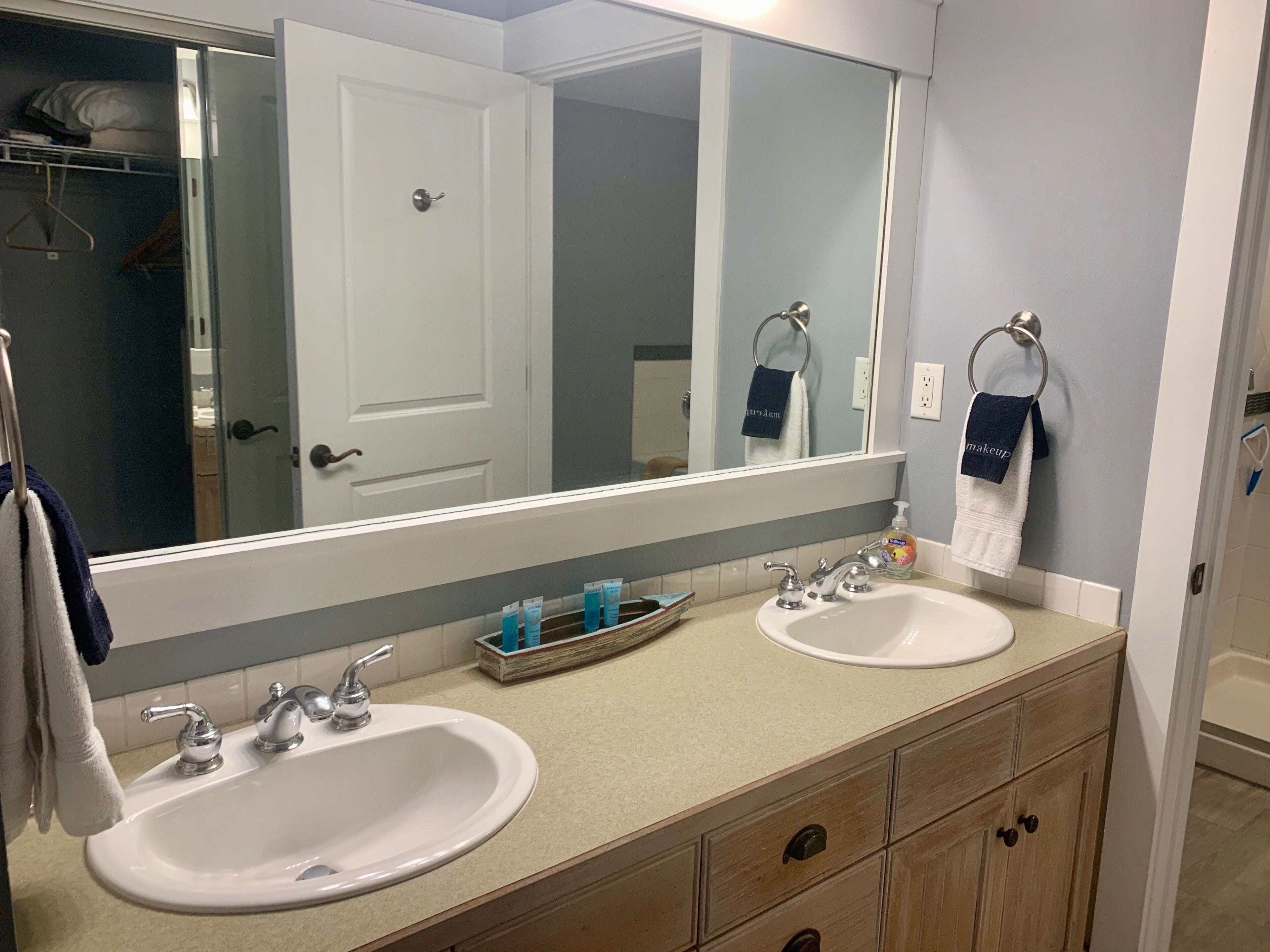 A bathroom with two sinks, a large mirror, and a towel rack.