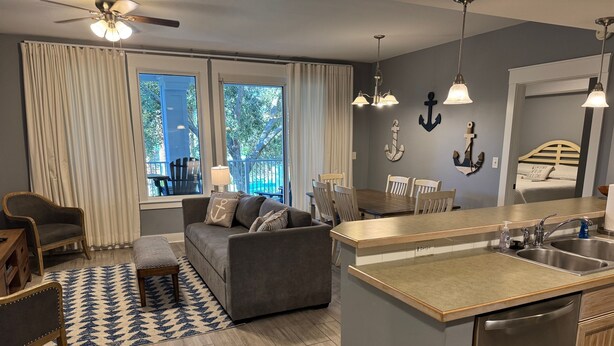 Una cocina moderna con lavavajillas incorporado, un comedor con mesa y sillas de madera, y una zona de estar acogedora con sofá y sillones.