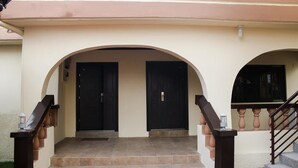 Uma entrada de edifício com um conjunto de degraus que levam a uma porta, emoldurada por duas arcadas.