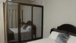 Quarto com cama, porta de correr de vidro e mesa de cabeceira.