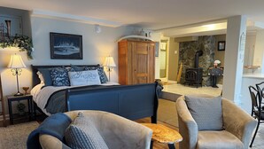 A cozy bedroom with a bed, two armchairs, a nightstand, and a lamp. - Maple Bay beachfront suite, just steps to your private beach patio (Duncan)