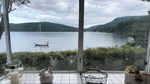 A kitchen with a view of a lake, a boat, and a mountainous landscape. - Maple Bay beachfront suite, just steps to your private beach patio (Duncan)