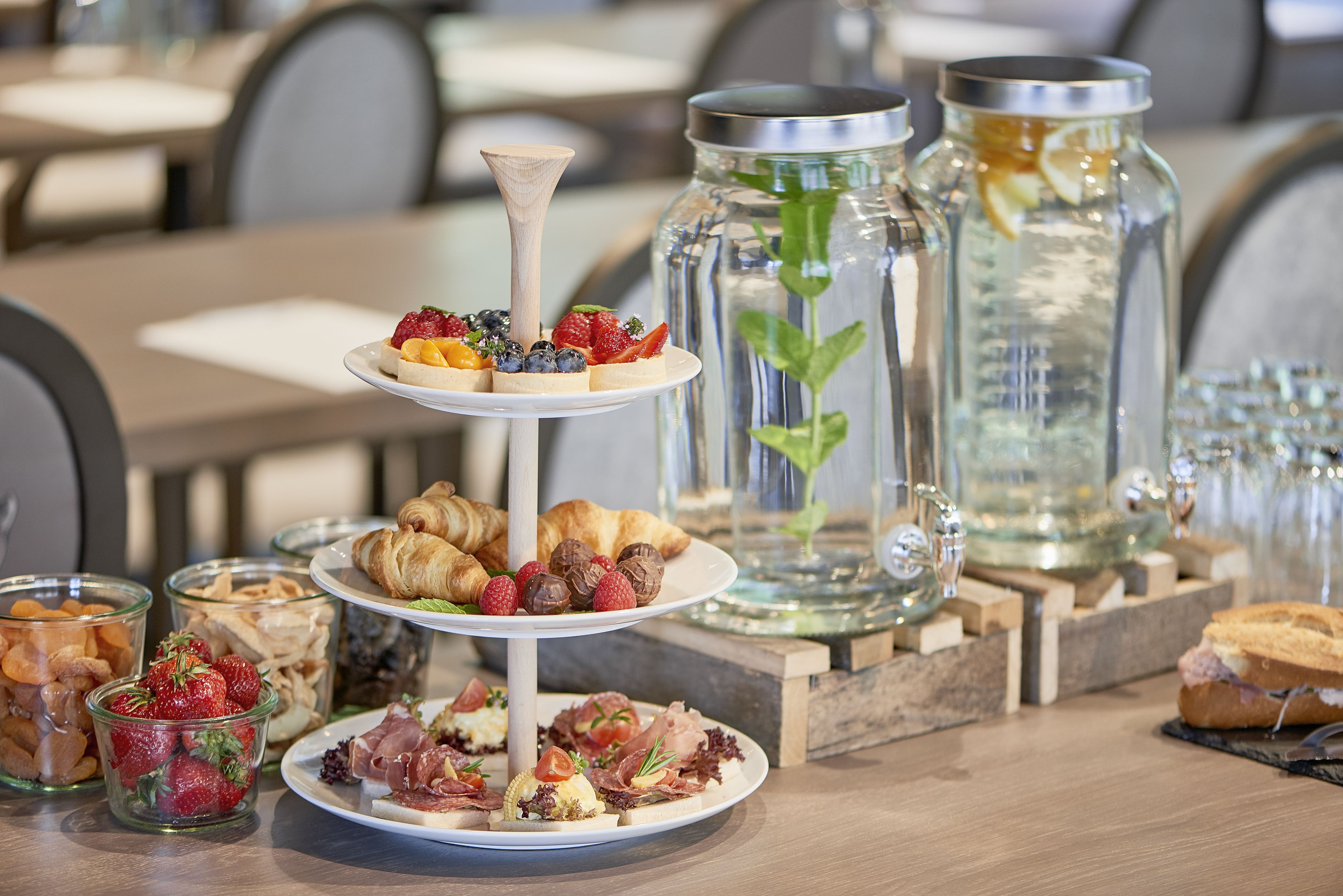 Ein mehrstöckiges Kuchenbuffet mit Gebäck, Früchten und Käse in einem Restaurant.