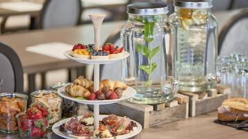 Ein mehrstöckiges Kuchenbuffet mit Gebäck, Früchten und Käse in einem Restaurant.