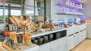 Un bufé de desayuno con panes, frutas y bebidas variadas.