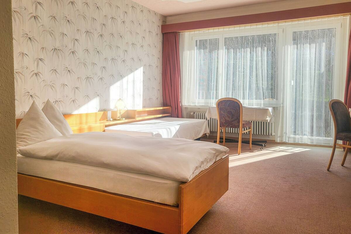 A hotel room with a bed, a desk, and a chair.