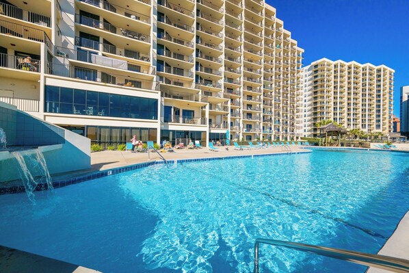Un hotel con piscina, varios balcones y un diseño arquitectónico moderno.