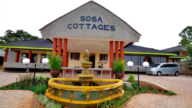 A building labeled "SOSA COTTAGES" with a reception area, a fountain, and a car parked in front. - Sosa Cottages (Gisambai)