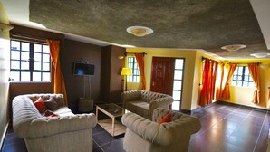 A living room with two sofas, a coffee table, and a TV. - Sosa Cottages (Gisambai)