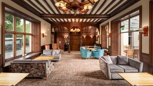 A spacious lobby with wooden beams, large windows, and a central chandelier. - Windermere Manor Hotel (Windermere)